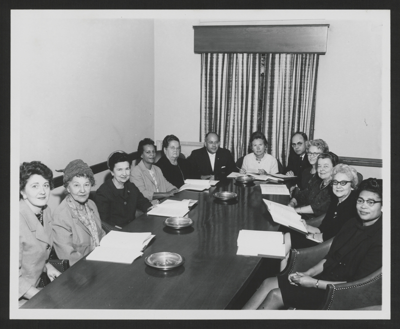 Photograph of the Commission on the Status of Women assembled for a meeting and an enclosed caption noting the members.; Caption: "Attending the 31st October meeting of the Governor's Commission on the Status of Women were left to right: Mrs. William T. Crisp, Mrs. Gladys A. Tillett, Dr. Ellen Winston, Mrs. Sarah Herbin, Dr. Rachel Davis, Mr. James E. Lambeth, Dr. Anne F. Scott (CHAIRMAN), Dr. William H. Cartwright, Mrs. C. Odell Matthews, Dr. Guion Johnson, Mrs. Ruth Easterling, Mrs. Anne Kennedy. Members of the Commission not present were: Mrs. C.W. Beasley, Miss Bonnie E. Cone, E. McArthur Currie, Oscar R. Ewing, Dr. Juanita Kreps, Dr. Arthur Larson."